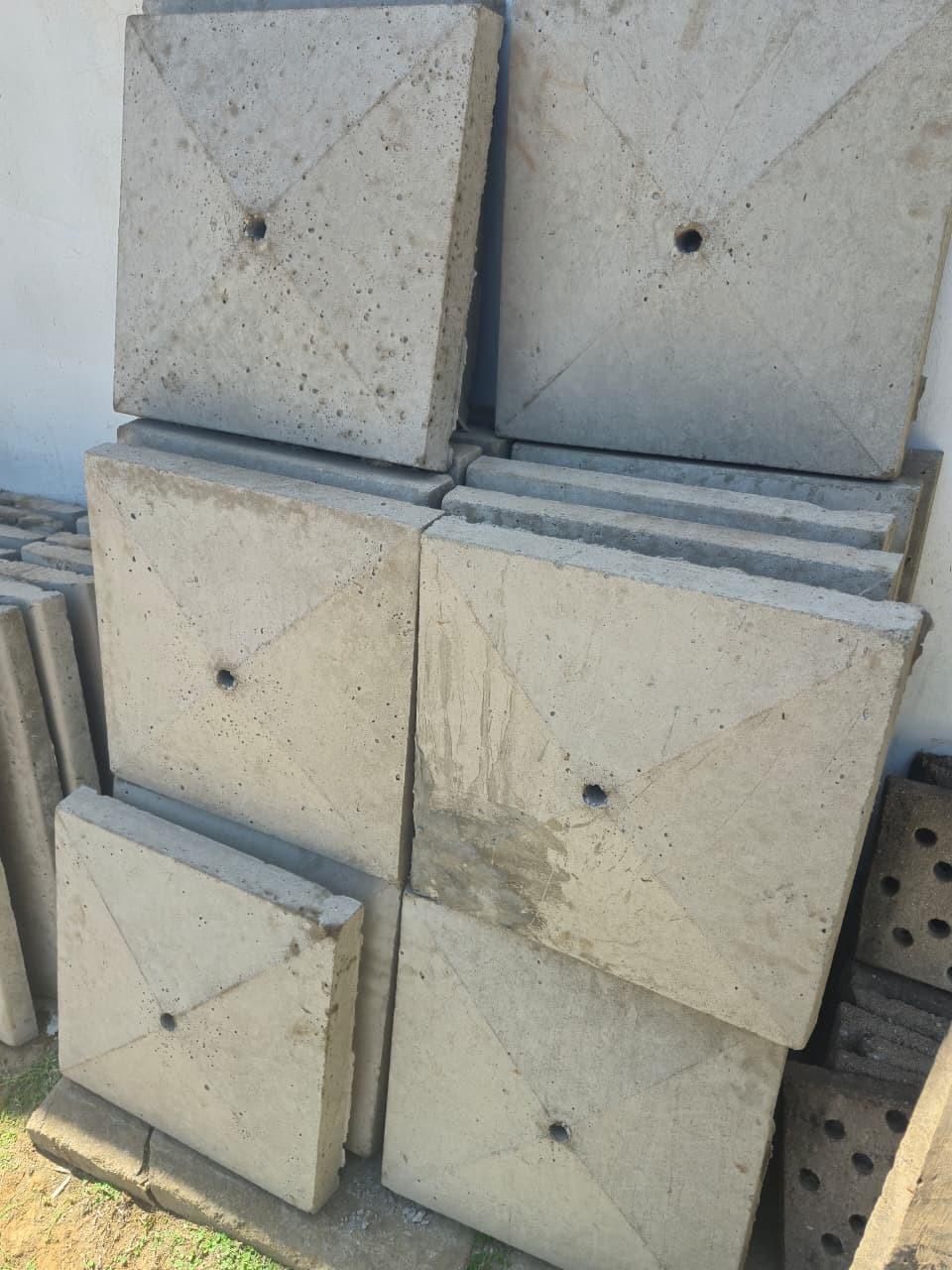 Square pillar caps stacked against a wall, each with a shallow pyramid top, the four cast ridges running to the corners and a centre hole for a light or finial.